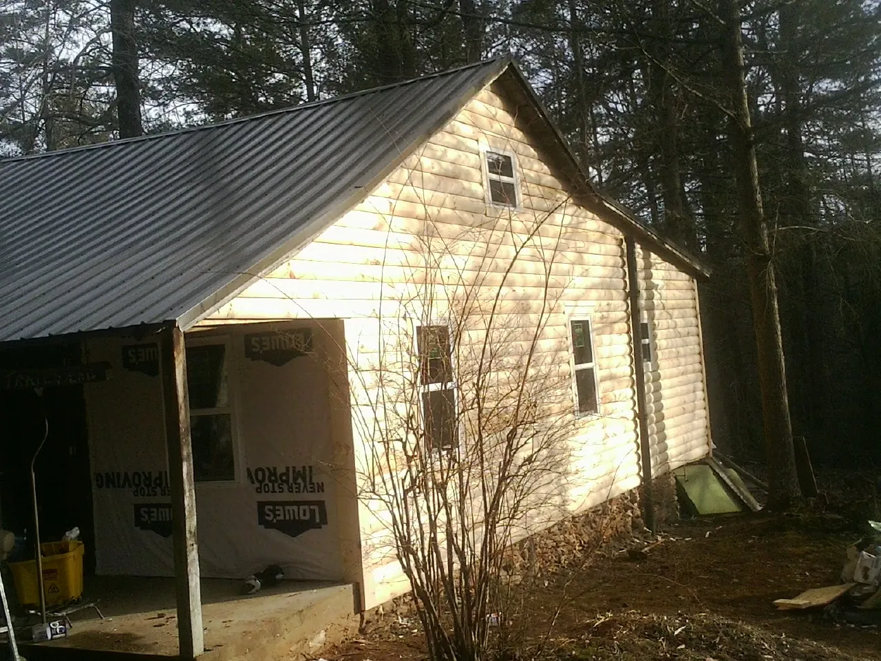 Log siding gable end under a dark metal roof edge in Sherburne