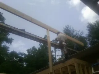 Carpenter setting a ridge beam over a new addition frame — Ice Dam Removal by Roofing Brothers in Sherburne