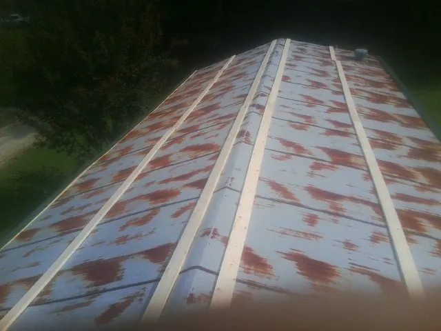 Rusted metal roof panels with new wood purlins before replacement — Storm Damage Roof Repair in Sherburne by Roofing Brothers