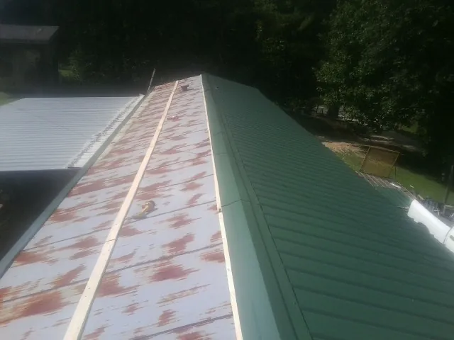 Old rusted panels beside newly installed green metal roofing — Wind Damage Roof Repair by Roofing Brothers in Sherburne