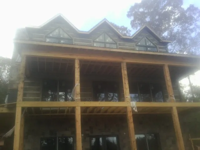 Dormers and porch framing on a large log home under construction — Roof Coating work by our crew in Sherburne