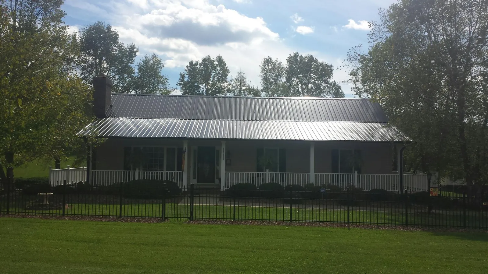 Gray metal roof on a brick ranch with a full width front porch — Gutter Guard Installation work by our crew in Sherburne