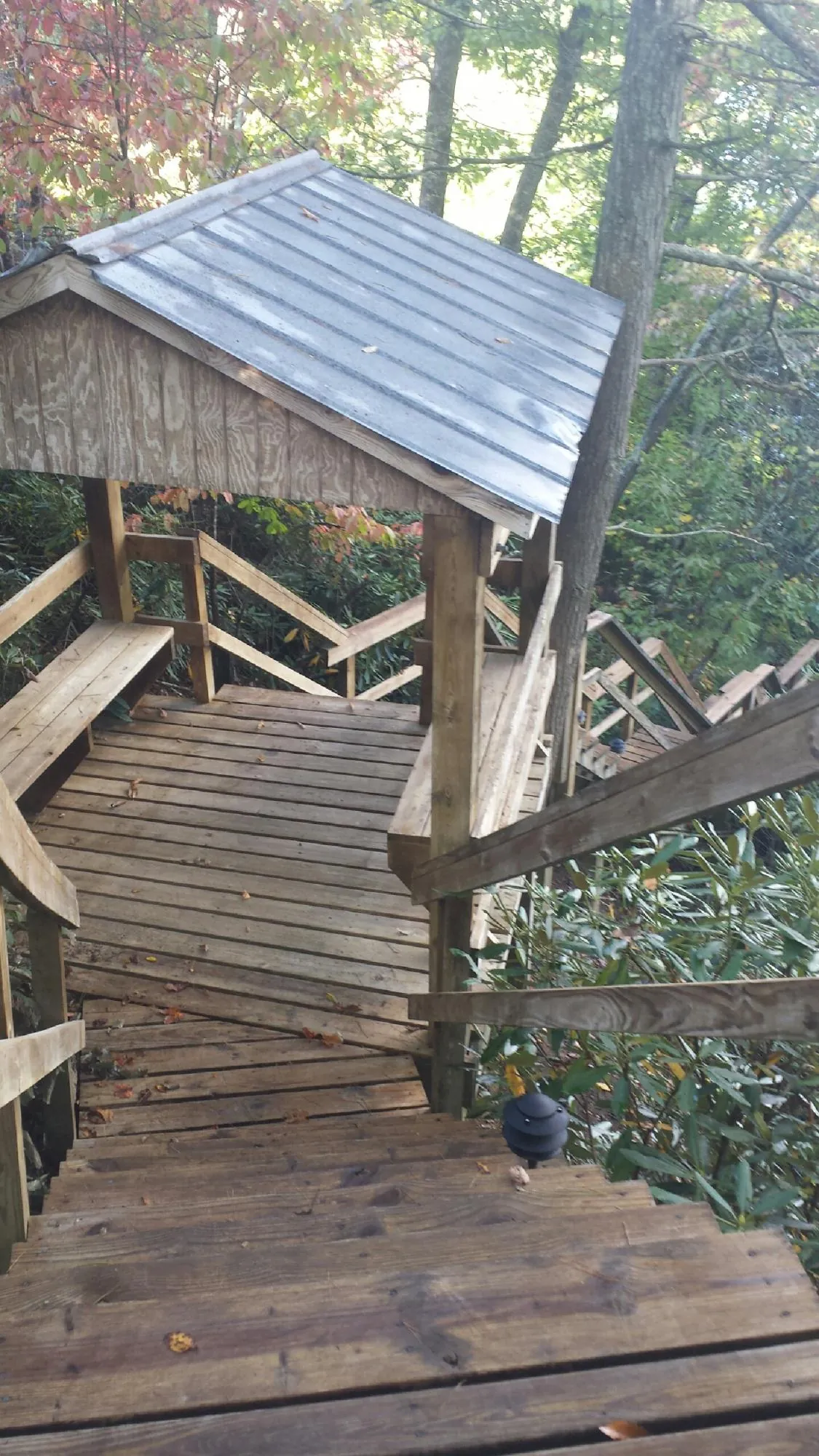 Metal roofed shelter over wooden steps on a wooded walkway — Skylight Repair & Installation work by our crew in Sherburne