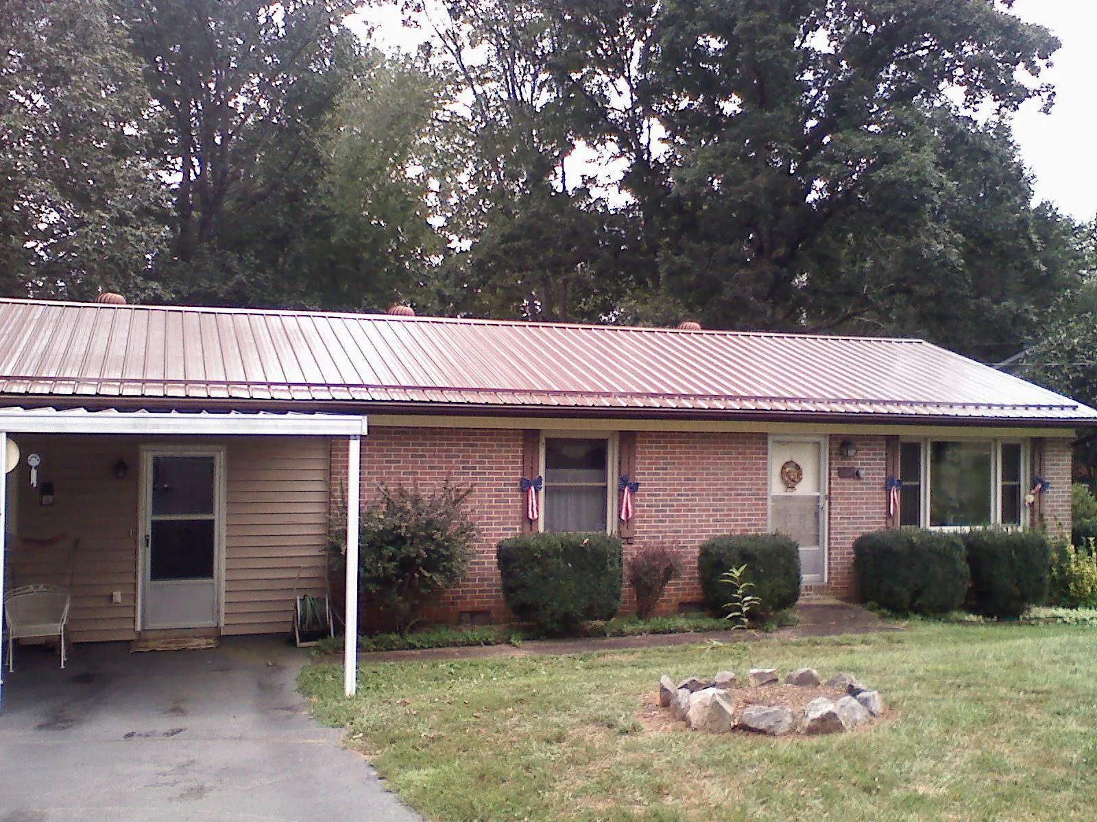 Bronze metal roof and carport on a brick ranch home — Roof Repair work by our crew in Sherburne